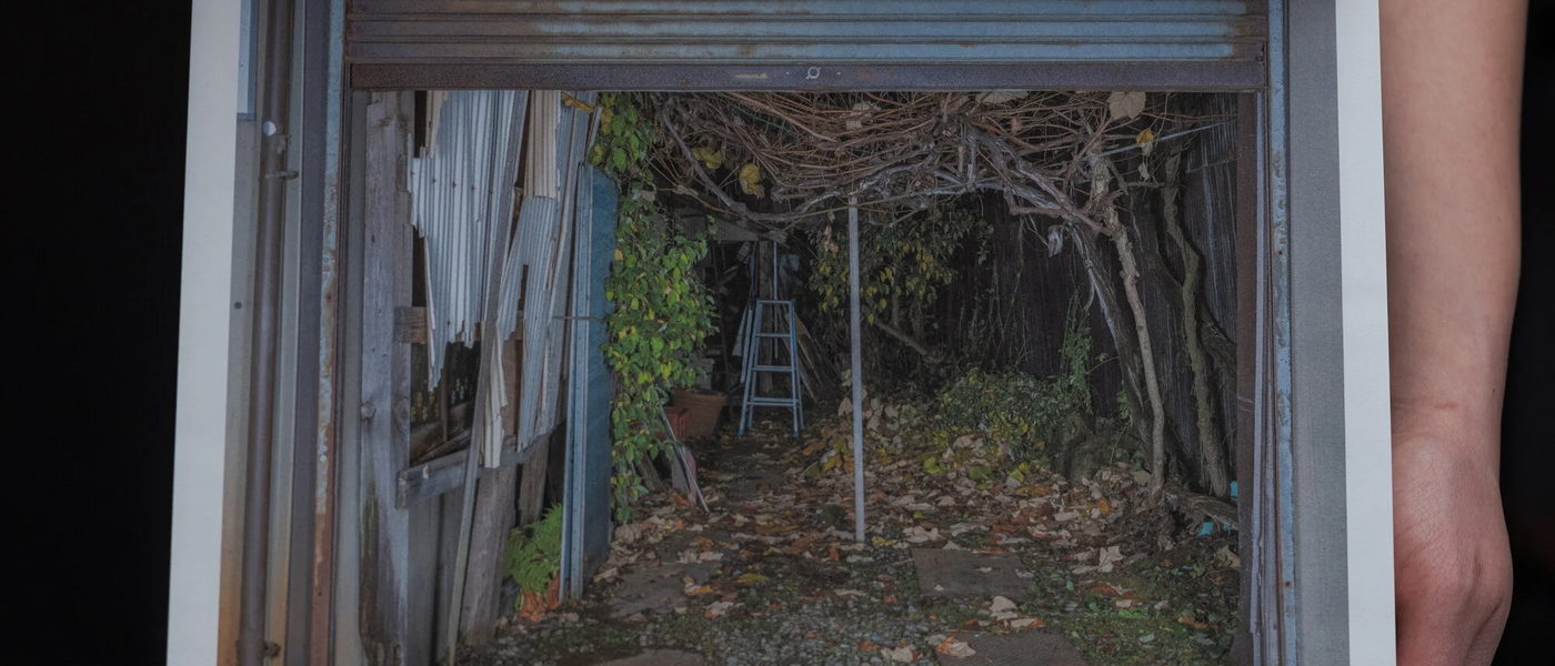 An open photo book held in two hands, a photograph of a garage filling the page